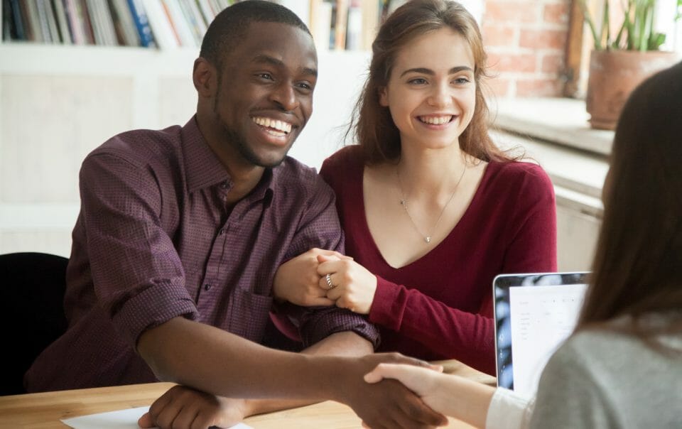 Cute couple shaking hands with appraiser