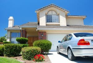 Large House with Shrubs and Car Parked in Driveway