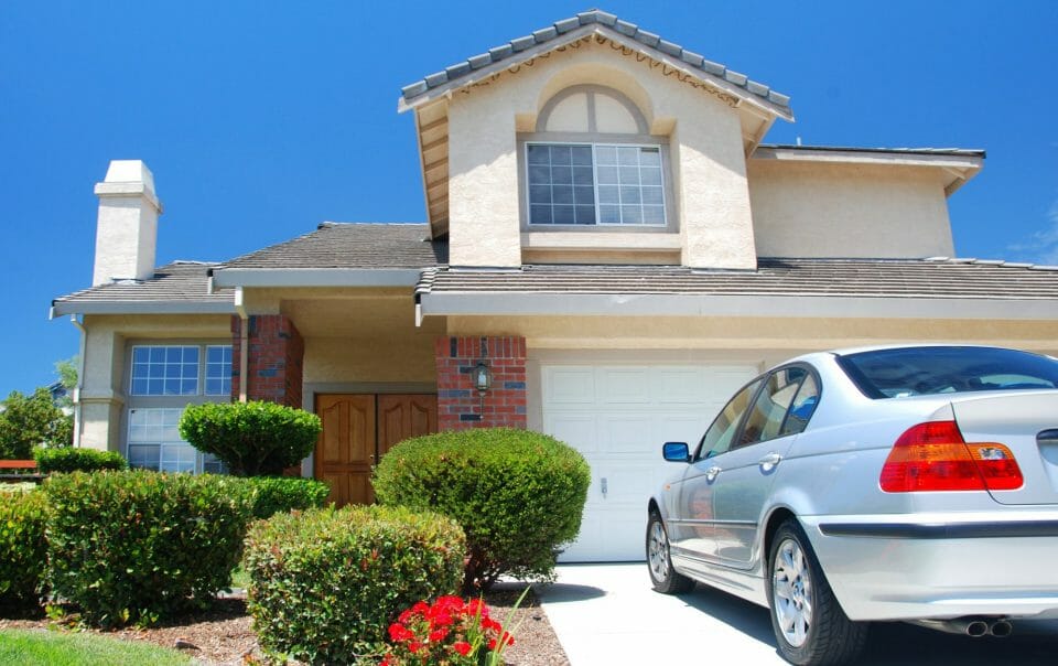 Large House with Shrubs and Car Parked in Driveway