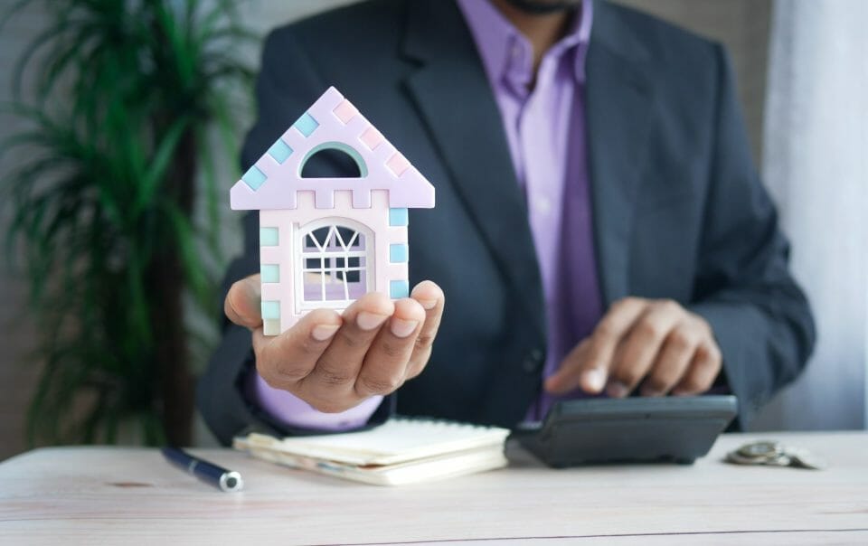 Business Man Holding Tiny House